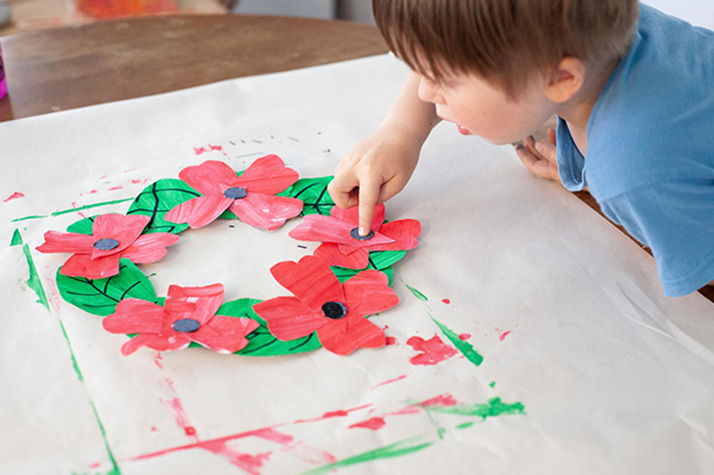 Child making a poppy wreath for Remembrance Day
