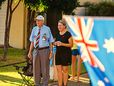 Veteran and woman commemorating on lawn ANZAC Day