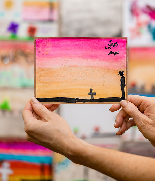 Two hands holding up a colourful Postcards of Honour submission