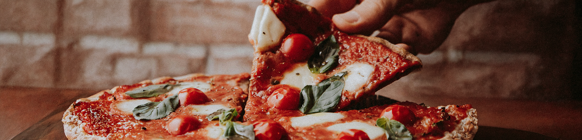 Person picking up a slice of pizza