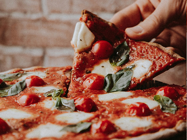 Person picking up a slice of pizza
