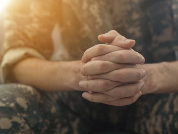 Defence personnel sitting with hands clasped